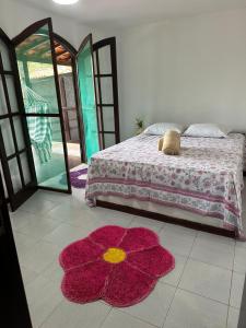 um quarto com uma cama e um tapete de flores vermelhas em Casa PraiaRasa em Armacao dos Buzios