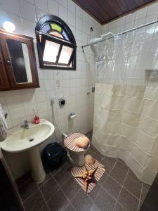 uma casa de banho com um chuveiro, um WC e um lavatório. em Casa PraiaRasa em Armacao dos Buzios