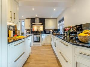 a large kitchen with white cabinets and black counter tops at Creamore Grove in Wem