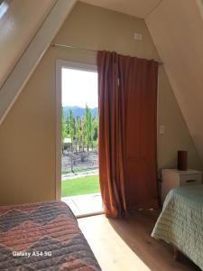 a bedroom with a bed and a large window at Cabañas Alpinas in Mendoza