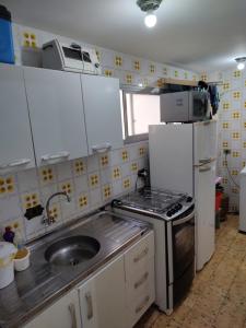 a kitchen with a sink and a stove and refrigerator at Apartamento Caiobá Pé na areia. Quadra do Mar. in Matinhos