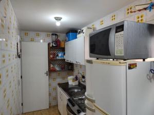 een keuken met een magnetron en een koelkast bij Apartamento Caiobá Pé na areia. Quadra do Mar. in Matinhos