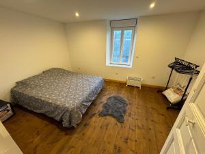 1 dormitorio con cama, ventana y suelo de madera en Charmant grand Appartement, en Serdinya