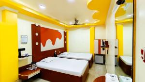 Duas camas num quarto com paredes amarelas e brancas em Hotel Samrat em Baharampur