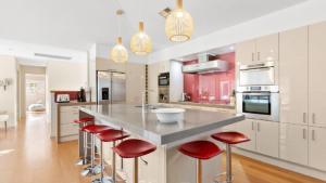 a kitchen with a large island with red bar stools at Marley's Retreat - Patonga Beach in Patonga Beach