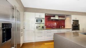 a kitchen with white cabinets and stainless steel appliances at Marley's Retreat - Patonga Beach in Patonga Beach