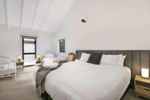 1 dormitorio blanco con 1 cama grande y 1 silla en Comrie, Bundanoon, en Bundanoon
