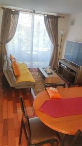 un soggiorno con un tavolo e una televisione di Departamento La Serena, amoblado, 2 habitaciones, a una cuadra de la playa a La Serena