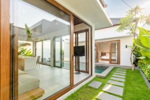 an open living room with sliding glass doors and a tv at J4 Villas Sanur in Sanur