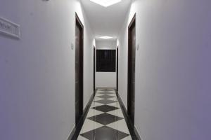 - un couloir avec un sol en damier et des portes noires dans l'établissement OYO Flagship V R Residency Near Sri Amruth Chithra Mandira, à Bangalore