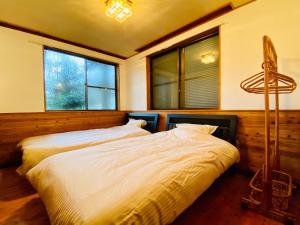 Aso - Cottage - Vacation STAY 83363 في آسو: سريرين في غرفة نوم مع نافذتين