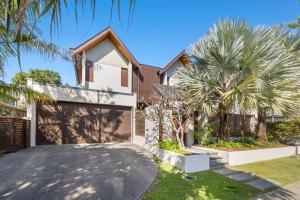 a house with a garage and a palm tree at Kingscliff Balinese Beachfront Retreat in Kingscliff
