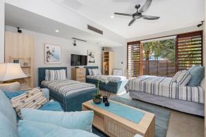 a living room with blue furniture and a ceiling fan at Kingscliff Balinese Beachfront Retreat in Kingscliff +35 photos