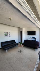Sala de estar con 2 camas negras y mesa en Apartasol Santa Fe de Antioquia - Ciudadela Santa Fe, en Santa Fe de Antioquia