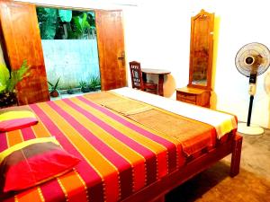 1 dormitorio con 1 cama con una manta a rayas de colores en Mount Rest Villa, en Hikkaduwa