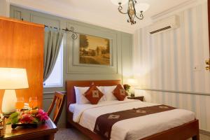 a bedroom with a bed and a table with a lamp at Ben Thanh Boutique Hotel in Ho Chi Minh City