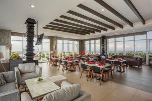 a restaurant with tables and chairs and windows at Swiss-Belhotel Jambi in Jambi