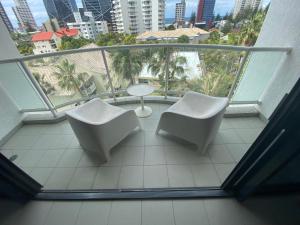 two chairs and a table on a balcony with a city at Oaks resort in Gold Coast