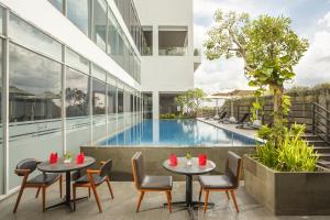 a hotel patio with tables and chairs next to a swimming pool at Swiss-Belhotel Jambi in Jambi