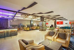 a lobby with chairs and tables and a bar at Swiss-Belhotel Jambi in Jambi