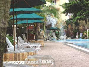 a group of chairs and umbrellas next to a swimming pool at Ruiyas Sea View Condominium PortDickson in Port Dickson