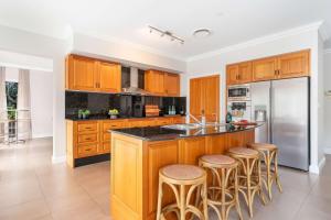una cocina con armarios de madera y una isla con taburetes. en Westbrook, Kangaroo Valley, en Valle Kangaroo