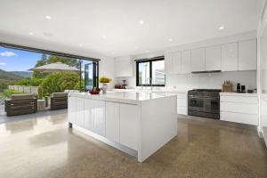 a kitchen with white cabinets and a large window at Serendipity, Kangaroo Valley in Barrengarry