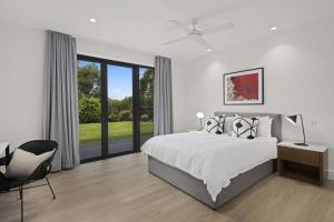 a white bedroom with a large bed and a chair at Serendipity, Kangaroo Valley in Barrengarry