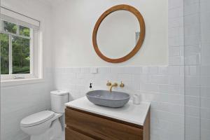 a bathroom with a sink and a toilet and a mirror at Paddington, Kangaroo Valley in Barrengarry