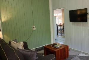 JDs Tropical stays في كيرنز: غرفة معيشة مع أريكة وتلفزيون على الحائط