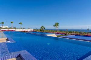 a swimming pool with blue water and palm trees at Lumina at Vista Velas II Los Cabos in El Pueblito