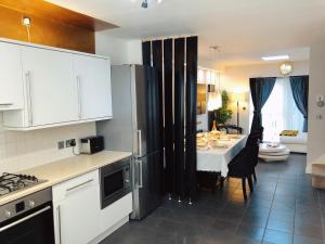 cocina con armarios blancos y comedor con mesa en Manchester City home with parking, en Mánchester