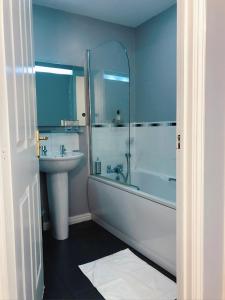 y baño con bañera, lavamanos y ducha. en Manchester City home with parking, en Mánchester