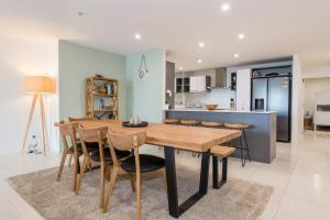 Una cocina y un comedor con mesa y sillas de madera. en Chilling at the Cayman, en Mount Maunganui