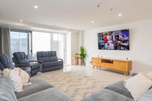 sala de estar con 2 sofás y TV en la pared en Chilling at the Cayman, en Mount Maunganui