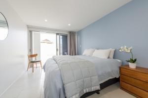 Un dormitorio blanco con una cama y una silla. en Chilling at the Cayman, en Mount Maunganui 25 fotos más