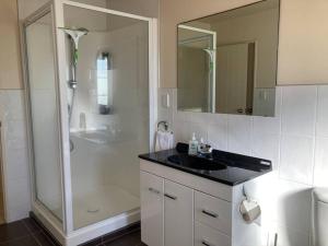 Un baño blanco con lavabo y ducha. en Marine Magic, en Mount Maunganui 18 fotos más