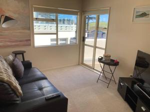 Una sala de estar con un sofá de cuero y una puerta corrediza de vidrio. en Marine Magic, en Mount Maunganui