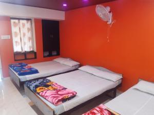 3 camas en una habitación con pared de color naranja en Riverview homestay, en Vālpārai