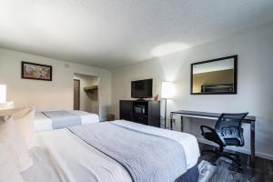 een hotelkamer met 2 bedden, een bureau en een stoel bij Econo Lodge Cleveland Southeast - Kent in Streetsboro