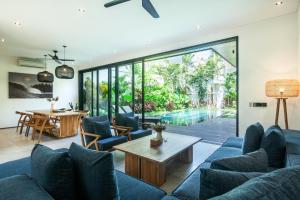 un soggiorno a pianta aperta con divani blu e tavolo di Seaside Escape 4br Villa, 190m To Canggu Beach a Canggu