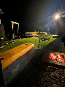 a bench sitting next to a fire in a yard at night at Cabana Alpes in São Bento do Sapucaí