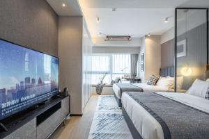 a hotel room with two beds and a flat screen tv at BORUISI Executive Apartment in Shenzhen