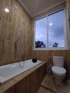 a bathroom with a tub and a toilet and a window at Saira Hotel dan Homestay Syariah in Sleman
