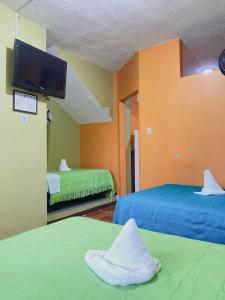 a room with two beds and a flat screen tv at Moonlight, Galápagos in San Cristobal