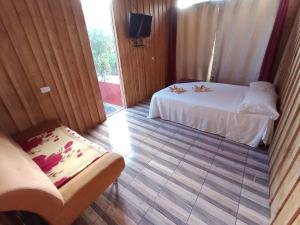 Habitación de hotel con cama y sofá en Cabaña Vistas De La Amistad, en Coto Brus