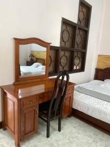 a bedroom with a desk with a mirror and a bed at Homestay 484 in Pleiku