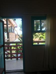 uma porta aberta com vista para um alpendre em Paikea Hostel Praia do Rosa na Praia do Rosa
