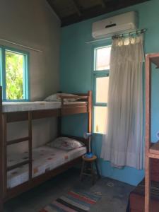 a bedroom with two bunk beds and a window at Paikea Hostel Praia do Rosa in Praia do Rosa