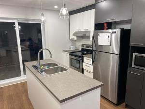 a kitchen with a sink and a refrigerator at Unactivated in Longueuil